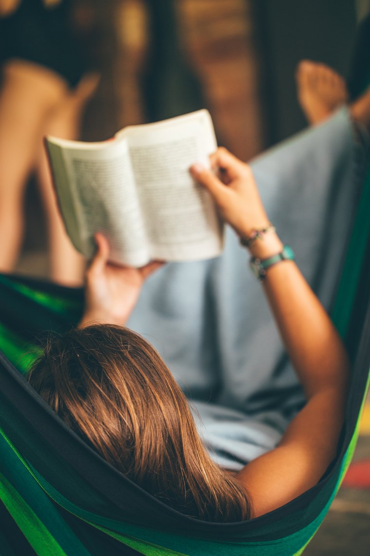 A person reading on a hammock.